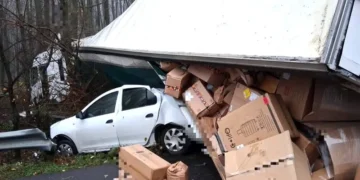 Un tir cu colete s-a răsturnat peste o mașină oprită